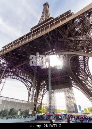 Unter dem Eiffelturm stehen Menschen Schlange, um zur Aussichtsplattform zu gelangen Stockfoto