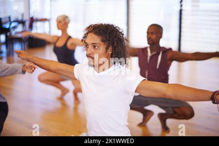 Fit und flexibel bleiben. Eine Gruppe junger Tänzer hockt in einem Tanzstudio. Stockfoto