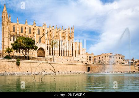 Seitlicher Blick auf die gotische Architektur der Kathedrale La Seu von St. Mary hinter der Stadtmauer von Palma de Mallorca und dem Teich des öffentlichen Parc de la mar. Stockfoto