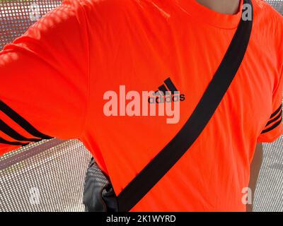 Tjumen, Russland-30. August 2022: Adidas Logo auf einem orangefarbenen T-Shirt. Adidas ist ein deutscher multinationaler Konzern für die Herstellung von Bekleidung und Fußbekleidung Stockfoto