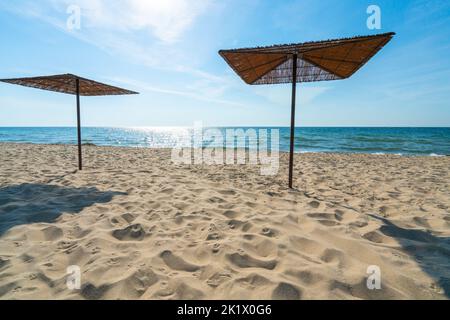 Schilf-Sonnenschirme am ansonsten leeren Sandstrand an einem schönen sonnigen Sommertag. Ostsee, Hel, Polen. Urlaub, Freizeit, Sommerurlaub. Stockfoto