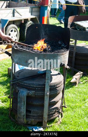 Schmied heizt in einer Kohleschmiede im Freien eine Eisenstange auf Stockfoto