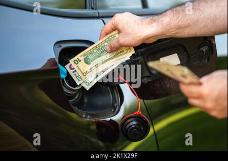 Hand of man, die Geld in den Tank des Autos, Nahaufnahme, Konzept der teuren Kraftstoff, Kraftstoff Krise steckt Stockfoto