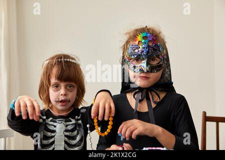 Kinder in halloween Kostümen auf weißem Wandhintergrund Stockfoto