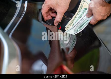 Hand of man, die Geld in den Tank des Autos, Nahaufnahme, Konzept der teuren Kraftstoff, Kraftstoff Krise steckt Stockfoto