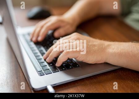Nahaufnahme der männlichen Hände mit Laptop. Der Mensch arbeitet zu Hause aus der Ferne. Distanzauftrag Stockfoto