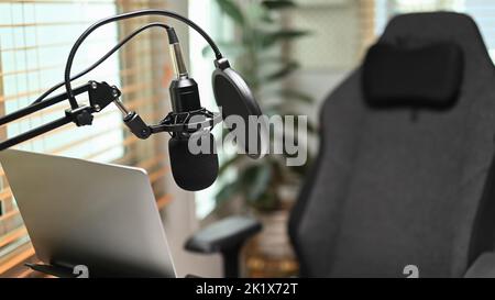 Ein professionelles Kondensatormikrofon, Laptop-Computer im Heimstudio-Interieur. Entertainment, Podcasts und Technologiekonzept Stockfoto