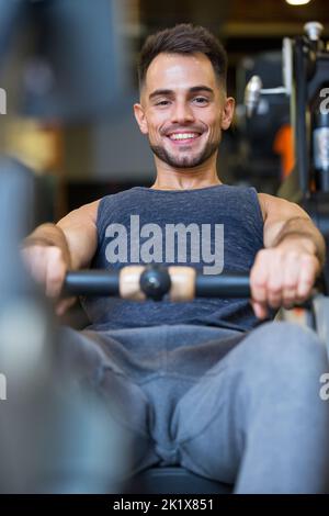 Glücklicher Mann beim Training auf dem Rudergerät Stockfoto