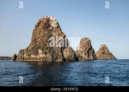 Die Faraglioni oder Isole dei Ciclopi (Zyklopen-Inseln), eine Gruppe vulkanischer Basaltmeeres, stapeln sich vor der Küste von Aci Trezza, Sizilien, Italien Stockfoto