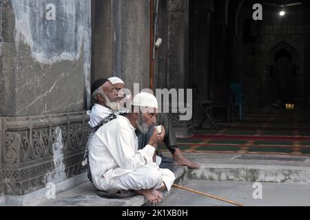 Der älteste muslimische Mann sitzt neben der Moschee und trinkt Tee in burhanpur Madhya Pradesh Stockfoto