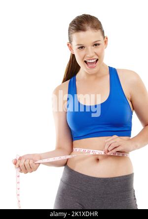 Es ist großartig, die Ergebnisse zu sehen. Ein hübsches Mädchen im Teenageralter, das ihre Taille misst und glücklich aussieht. Stockfoto