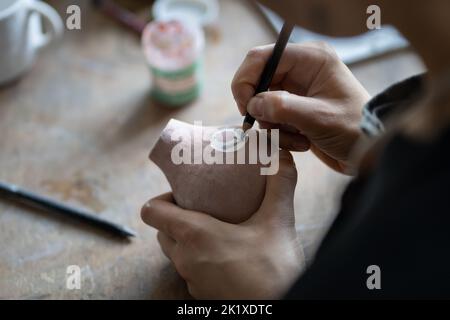 Craftsmaster macht interessante Skizzenzeichnung Symbol auf Krug mit Bleistift für die Erstellung von Entwurf Stockfoto