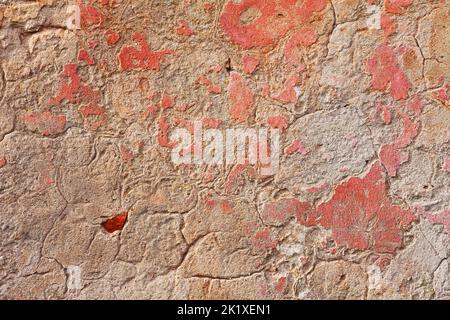 Alte Wand mit zerkratztem Gips und Resten von rosa Farbe - grunge Hintergrundstruktur Stockfoto