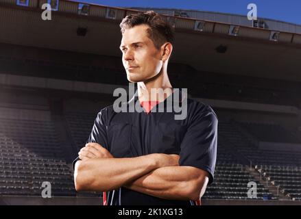 Selbstbewusst vor dem Spiel. Ein junger Athlet, der in den Lichtern des Stadions steht. Stockfoto