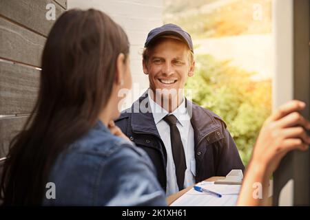 Empfang eines Pakets von ihrem freundlichen Lieferer. Ein junger Mann, der eine Lieferung an eine Frau zu Hause macht. Stockfoto