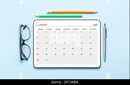 Tablet mit Kalender-App, Brille und Bürobedarf auf dem Schreibtisch. Draufsicht flach liegend Stockfoto