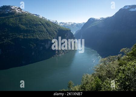 Wunderschöne Landschaften in Norwegen. Vestland. Wunderschöne Landschaft des Geiranger Fjords vom Aussichtspunkt Ornesvingen aus. Verschneite Berge, Bäume und Wasserfälle. Stockfoto