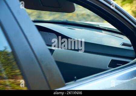 Teil eines vorderen Fahrzeuginnenraums durch ein offenes Fenster Stockfoto