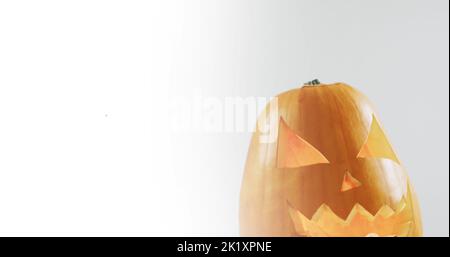 Bild von halloween Text über geschnitztem Kürbis auf grauem Hintergrund Stockfoto