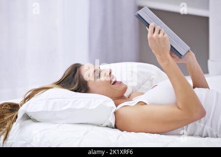 Das ist also gestern Abend passiert... eine Frau, die auf dem Bett lag, während sie ihren Laptop benutzte. Stockfoto