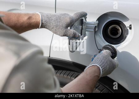 Mann öffnet die Luke des Gastanks des Autos. Fahrer öffnet den Gastank Stockfoto