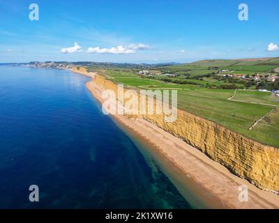 Blick aus der Luft auf die goldenen Sandsteinklippen am Bienenstrand von Burton Bradstock an der Dorset Jurassic Coast an einem heißen, sonnigen Herbsttag. Stockfoto