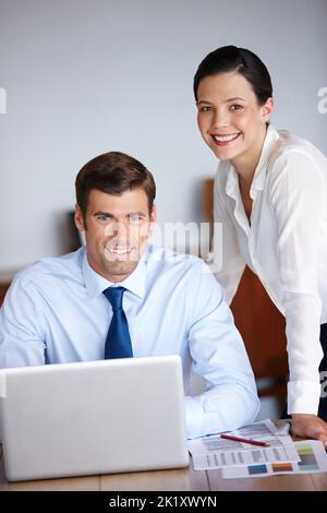 Fertig zum Abschluss. Porträt von zwei Geschäftskollegen, die in ihrem Büro einen Laptop benutzen. Stockfoto