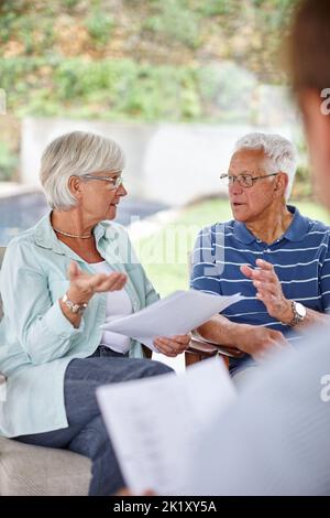 Verwirklichen Sie Ihre finanziellen Ziele. Überdrehte Aufnahme eines Treffens eines Finanzberaters mit einem älteren Paar zu Hause. Stockfoto