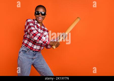 Foto von fröhlich positive Mädchen halten Baseballschläger toothy Lächeln haben Spaß isoliert auf orangen Hintergrund Stockfoto