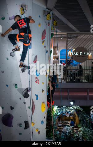 Kletter-Enthusiasten klettern an der Indoor-Kletterwand im Excelsior Shopping Center, Civic District Singapore Stockfoto