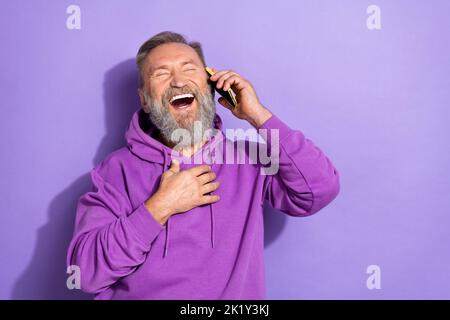 Foto von im Alter erlebt attraktiven Senior Mann halten Telefon reden Lachen Witz gute Laune leeren Raum auf lila Hintergrund isoliert Stockfoto