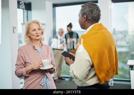 Ältere Schüler und Lehrer machen zwischen den Vorlesungen eine Pause und sprechen über Social Media Marketing. Stockfoto