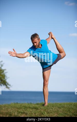 Hes war immer ein flexibler Typ. In voller Länge ein hübscher reifer Mann, der im Freien Yoga macht. Stockfoto