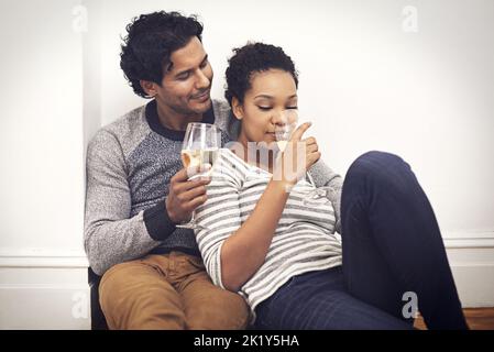 Ein glückliches Paar, das zu Hause zusammen Wein genießt. Stockfoto