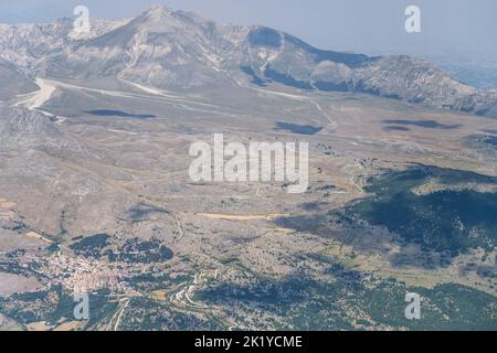 Luftaufnahme, aus einer kleinen Ebene, von Castel del Monte Dorf mit Campo Imperature Hochland im Hintergrund, aufgenommen von Süden in hellen Sommerlicht, Apenn Stockfoto