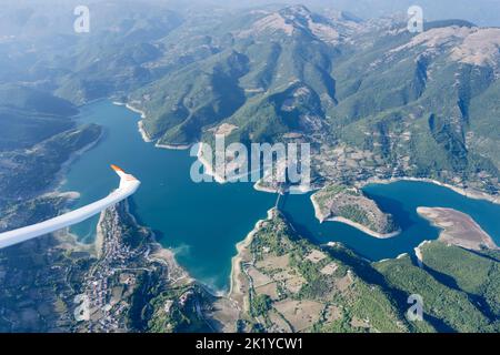 Luftaufnahme, von einem Segelflugzeug, von seinem Flügel im Flug über Turano See mit Colle di Tora und Castel di Tora Dörfer am Ufer, von oben in hell geschossen Stockfoto