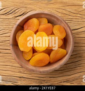 Getrocknete Aprikosen in einer Schüssel über einem Holztisch. Stockfoto