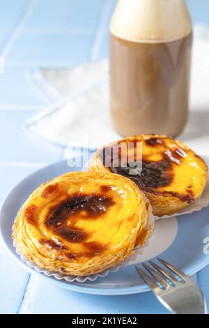 Nahaufnahme des portugiesischen Dessert Pastel de nata mit Kaffee auf blauen Fliesen Stockfoto