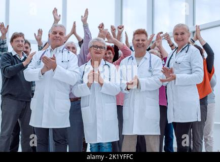 Ärzte und eine Gruppe reifer Menschen applaudieren Stockfoto