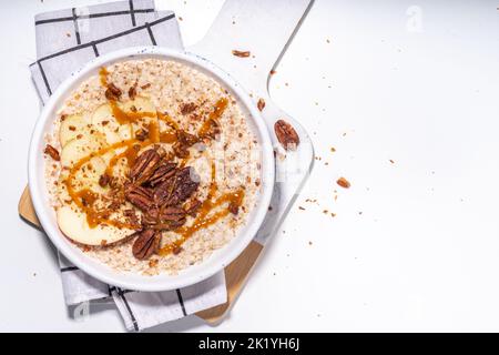 Einfaches, traditionelles amerikanisches Herbstfrühstück. Verzehrfertig Apfelkuchen Haferbrei Haferbrei mit Äpfeln, Pekannüssen und Karamell auf weißem Hintergrund Kopie s Stockfoto