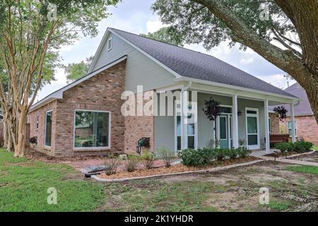 Eine schräge Vorder- und Seitenansicht eines akadischen renovierten Hauses mit Säulen, Gehwegen und einer farbenfrohen Eingangstür, die kürzlich mit dem wechselnden Real gekauft wurde Stockfoto