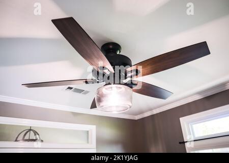 Eine weiße Ablagefläche mit dunklem Holz, modernem Ventilator und braunen Wänden Stockfoto