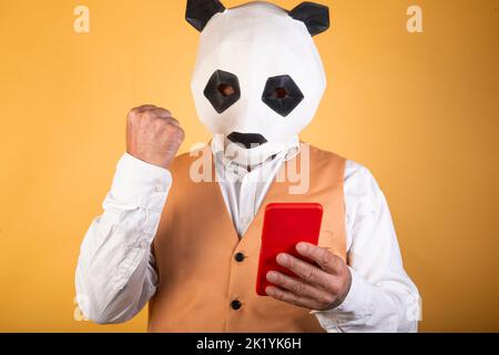 Mann in Anzug und Panda Maske mit einem Smartphone Stockfoto