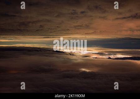 Hochgelegene Ansicht von Wolkenschichten über Lichtern aus der fernen Stadt Stockfoto