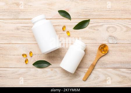 Omega-3 Kapseln liegen in einer weißen Flasche auf einem Tisch mit grünem Blatthintergrund. Fischöltabletten. Biologisch aktive Zusatzstoffe. omega 6, Omega 9, Vitam Stockfoto