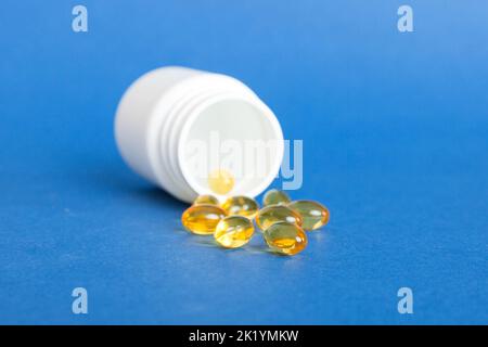 Weiche Geltabletten mit Omega-3-Öl, das aus der Pillenflasche aus der Nähe verschüttet wird. Gelkapseln Flasche weiße Oberfläche. Omega 3, Multivitamine, Kalzium, Antibiotika Stockfoto