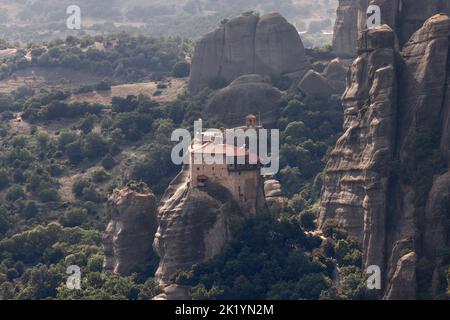 Panoramablick von oben auf das Heilige Kloster von Rousanou, das ursprünglich auf einem Gipfel der hoch aufragenden Felsskulptur von Meteora unter der Abendsonne errichtet wurde Stockfoto