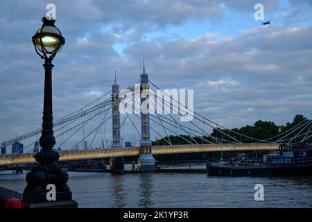 Blick auf die Albert Bridge von der Nordseite der Themse in London in der Abenddämmerung Stockfoto