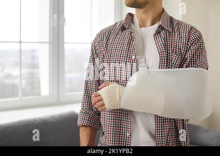 Der junge Mann, der sich an Arm, Hand, Handgelenk und Ellenbogen verletzt hat, trägt einen Verband und eine Schlinge Stockfoto