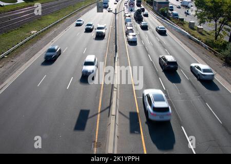 An einem sonnigen Morgen passiert unscharfer Verkehr auf einer belebten mehrspurigen Autobahn. Stockfoto
